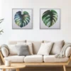 Monstera Study I and II limited editions above a calm beige sofa — numbered art editions for collectors who value quiet, hand-finished presence.
