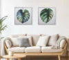 Monstera Study I and II limited editions above a calm beige sofa — numbered art editions for collectors who value quiet, hand-finished presence.