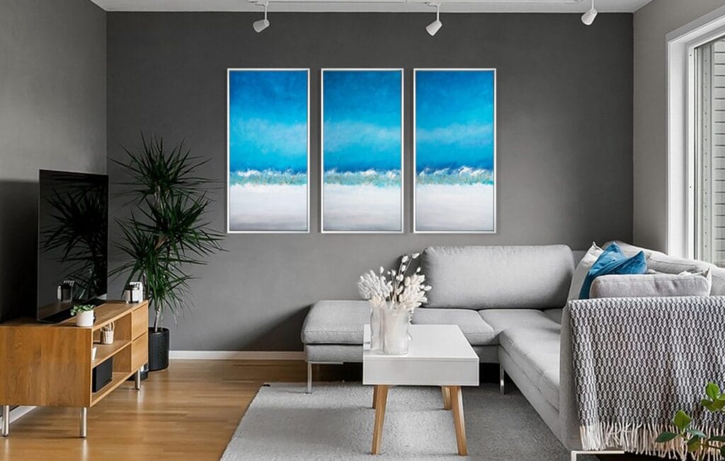 Coastal Horizon original acrylic triptych displayed above a white sofa in a bright modern living room.