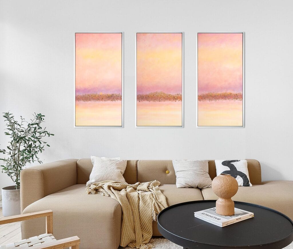 Dawnlight Reflections original acrylic triptych displayed above a beige sofa in a warm neutral living room.