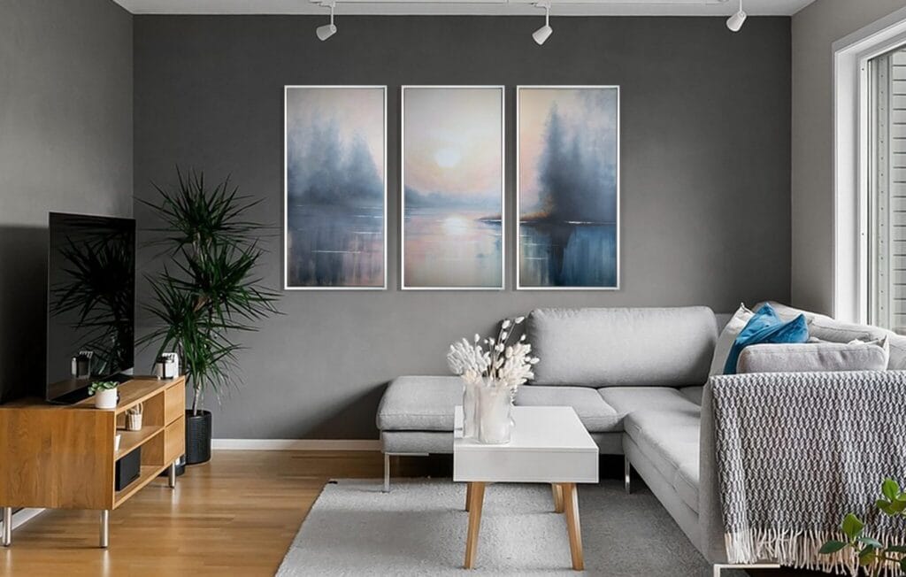 Mists of Serenity original acrylic triptych displayed above a gray sofa in a contemporary living room with warm wood accents.