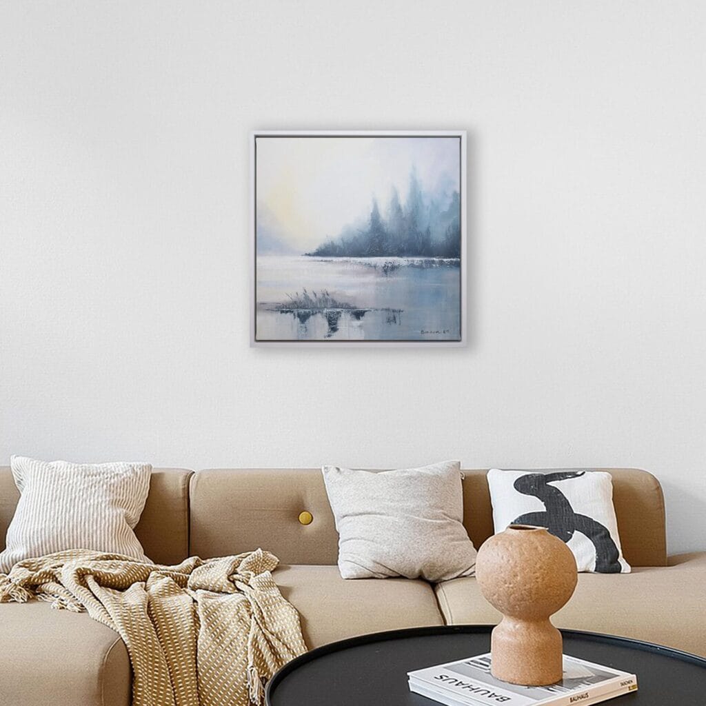 Silent Edge original framed artwork displayed above a neutral contemporary sofa with warm accent pillows.