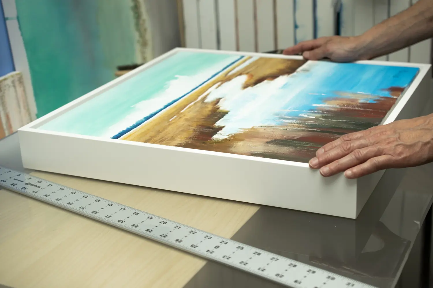 Framed coastal artwork being prepared by hand on the studio bench